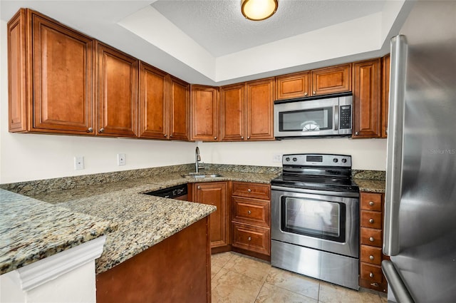 kitchen with stainless steel appliances, a textured ceiling, stone countertops, and sink