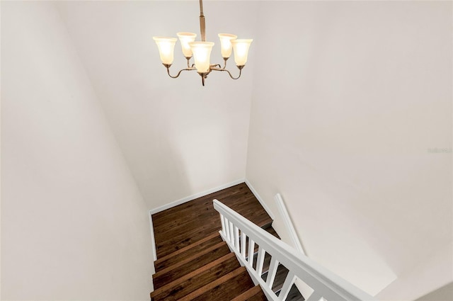 staircase with hardwood / wood-style flooring and a chandelier