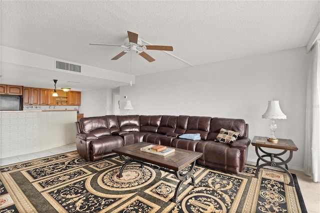 living room with ceiling fan and a textured ceiling