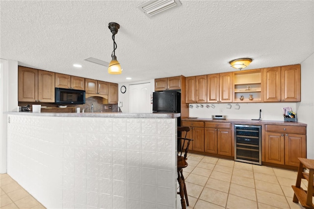 kitchen featuring pendant lighting, a textured ceiling, light tile patterned floors, black appliances, and beverage cooler