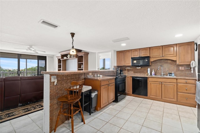 kitchen featuring decorative light fixtures, black appliances, a breakfast bar, sink, and ceiling fan