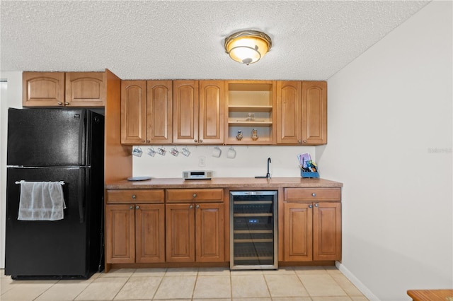 kitchen with black refrigerator, light tile patterned flooring, beverage cooler, and a textured ceiling