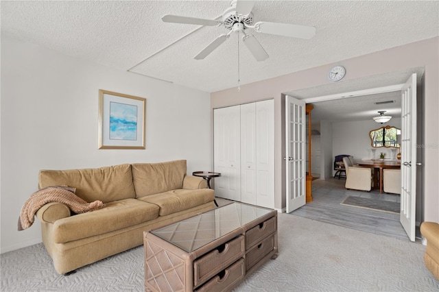 living room featuring light wood-type flooring, ceiling fan, and a textured ceiling