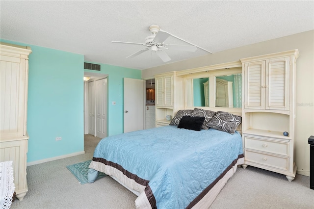 carpeted bedroom featuring ceiling fan and a textured ceiling