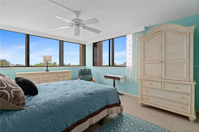 bedroom with a textured ceiling, light colored carpet, and ceiling fan