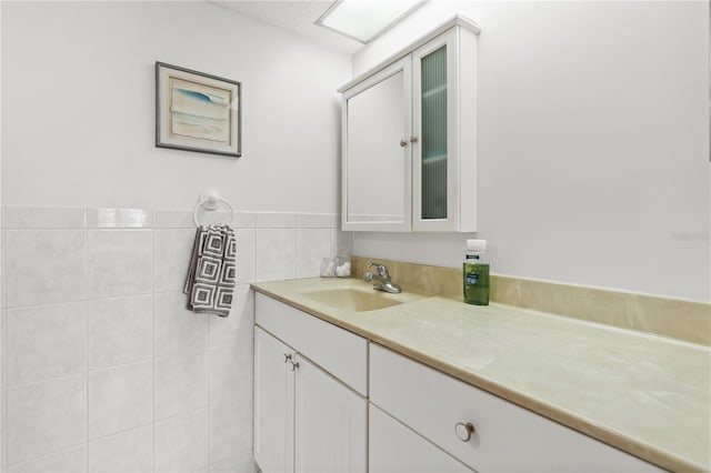 bathroom featuring vanity, a textured ceiling, and tile walls