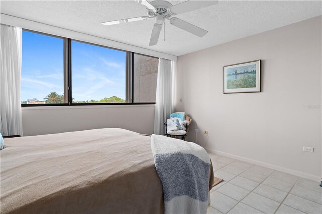 tiled bedroom with a textured ceiling and ceiling fan