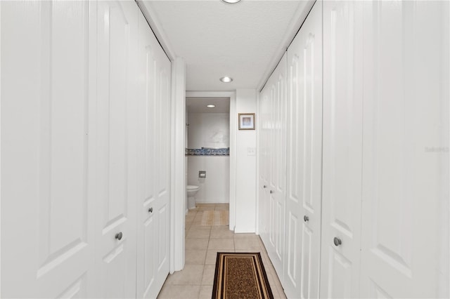 hall with a textured ceiling and light tile patterned flooring