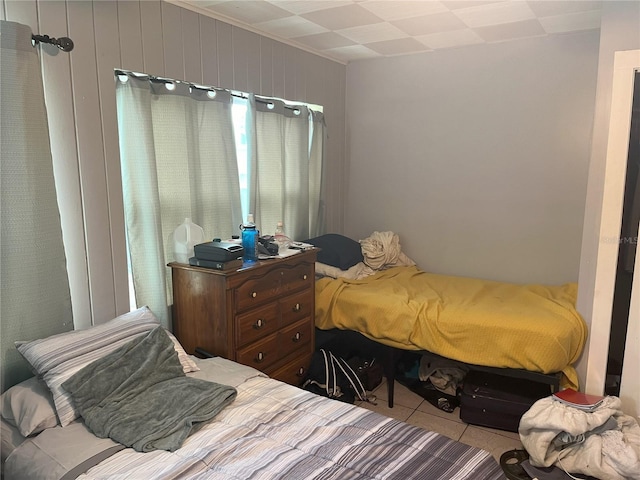 bedroom with wood walls and light tile patterned floors