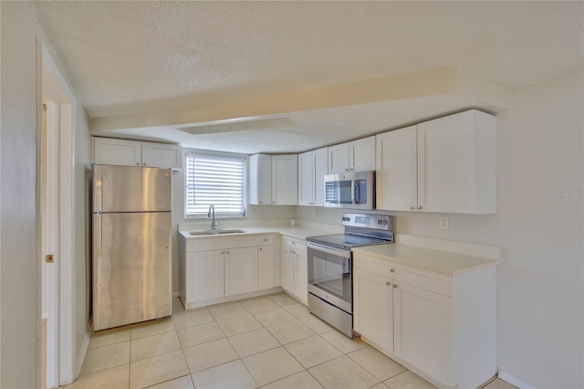 kitchen featuring a textured ceiling, white cabinetry, sink, and stainless steel appliances