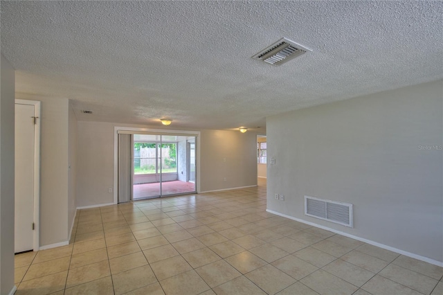 spare room with a textured ceiling and light tile patterned flooring