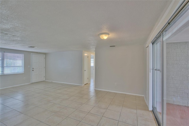 empty room featuring a textured ceiling and light tile patterned flooring