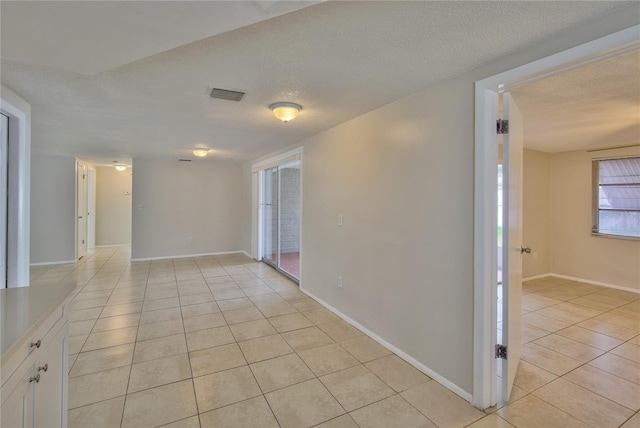 tiled empty room featuring a textured ceiling