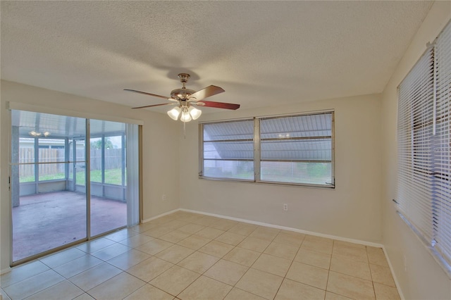 empty room with a textured ceiling, light tile patterned floors, and ceiling fan