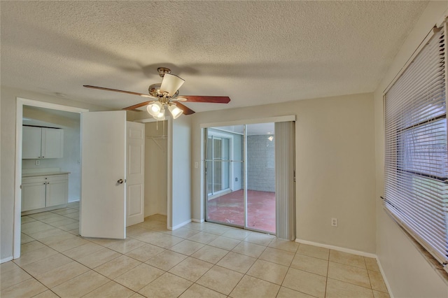 tiled spare room featuring a textured ceiling and ceiling fan