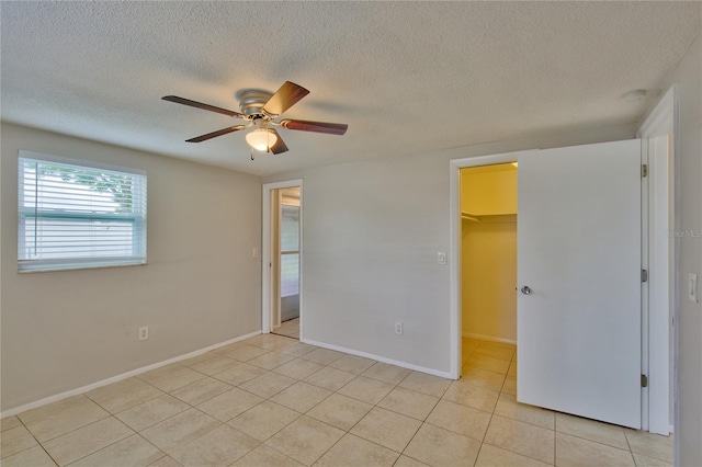 spare room with a textured ceiling, light tile patterned floors, and ceiling fan