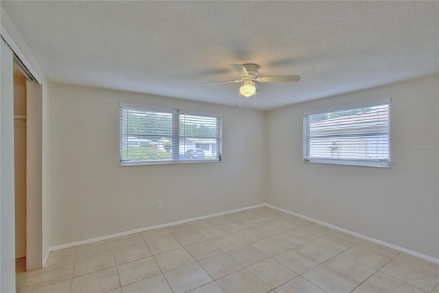 tiled empty room featuring a wealth of natural light, ceiling fan, and a textured ceiling