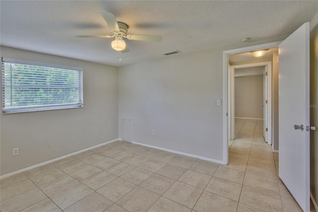 unfurnished room with a textured ceiling, light tile patterned floors, and ceiling fan