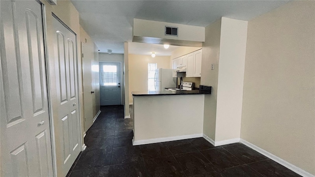 kitchen featuring baseboards, visible vents, freestanding refrigerator, white cabinets, and under cabinet range hood