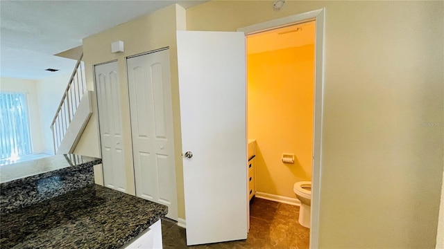 bathroom with a closet, baseboards, toilet, and vanity