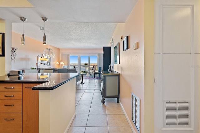 kitchen featuring a textured ceiling, pendant lighting, an inviting chandelier, and light tile patterned floors