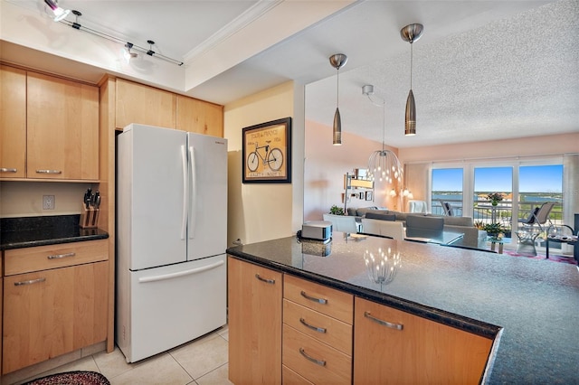 kitchen featuring dark stone counters, a textured ceiling, white fridge, light tile patterned floors, and decorative light fixtures