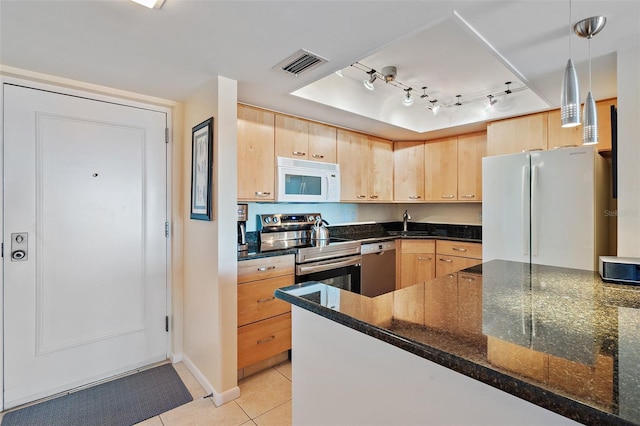 kitchen with appliances with stainless steel finishes, dark stone counters, light brown cabinets, and pendant lighting