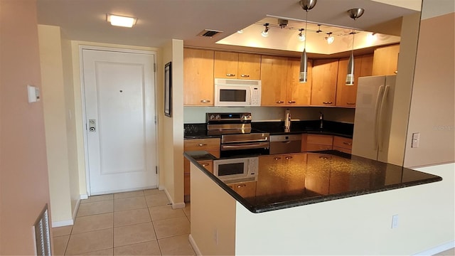 kitchen featuring light tile patterned flooring, hanging light fixtures, kitchen peninsula, appliances with stainless steel finishes, and dark stone countertops