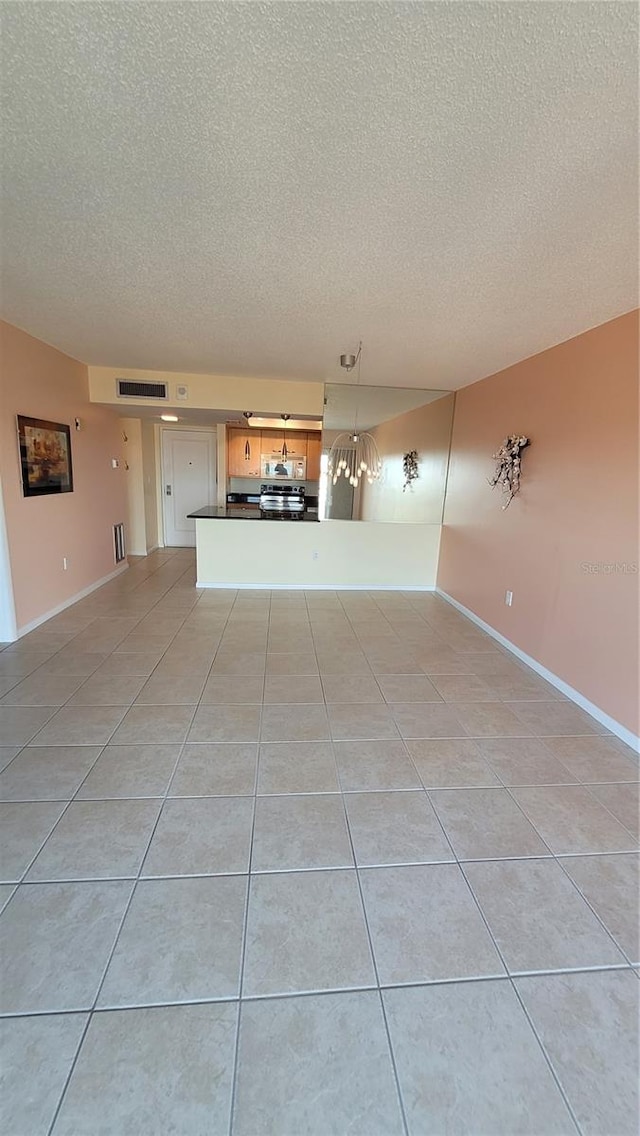 unfurnished living room featuring a textured ceiling and light tile patterned floors