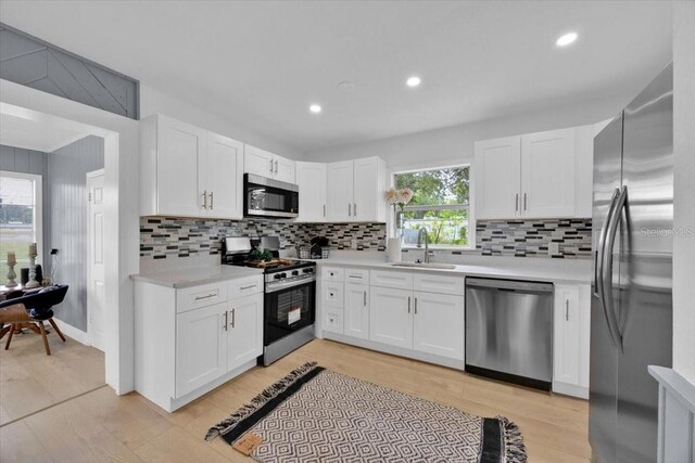 kitchen with sink, white cabinetry, stainless steel appliances, and a healthy amount of sunlight