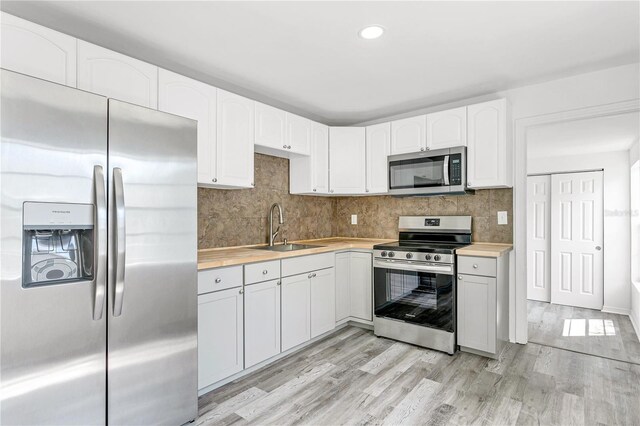 kitchen with white cabinets, stainless steel appliances, light hardwood / wood-style floors, and sink