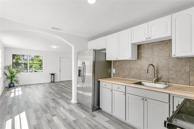 kitchen featuring light hardwood / wood-style floors, stainless steel fridge with ice dispenser, white cabinetry, and sink