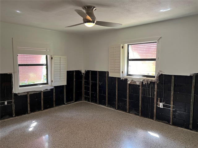 empty room featuring a wealth of natural light, ceiling fan, and a textured ceiling