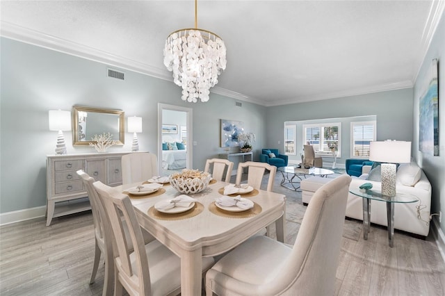 dining area featuring light hardwood / wood-style floors, crown molding, and an inviting chandelier