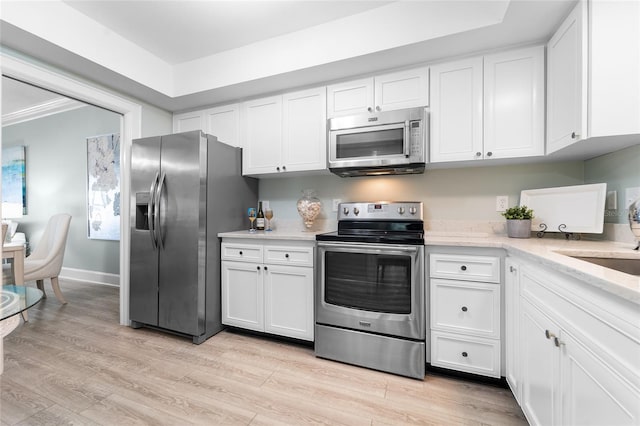 kitchen with sink, appliances with stainless steel finishes, light hardwood / wood-style floors, white cabinets, and ornamental molding