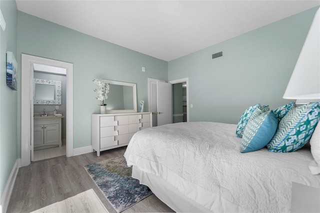 bedroom with connected bathroom, light hardwood / wood-style flooring, and sink