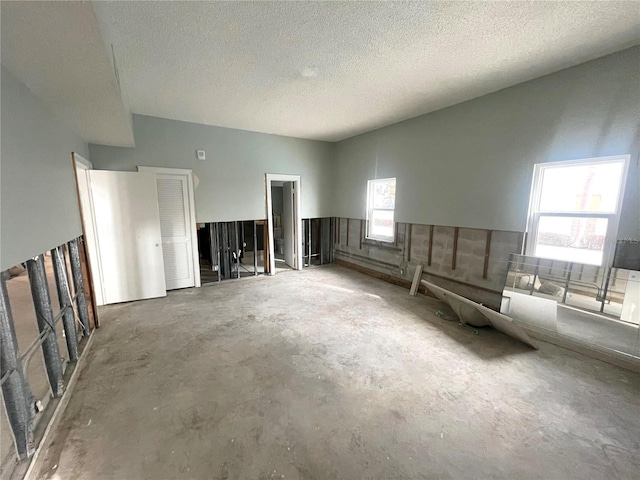 unfurnished living room featuring a textured ceiling and unfinished concrete flooring