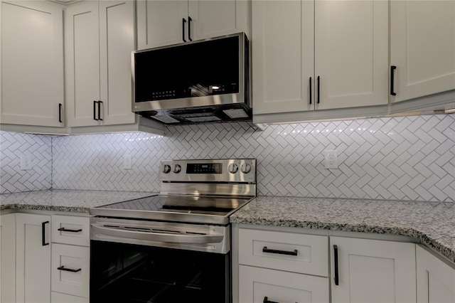 kitchen featuring white cabinets, light stone counters, stainless steel appliances, and decorative backsplash