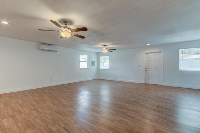 spare room featuring ceiling fan, a wall unit AC, and light hardwood / wood-style floors