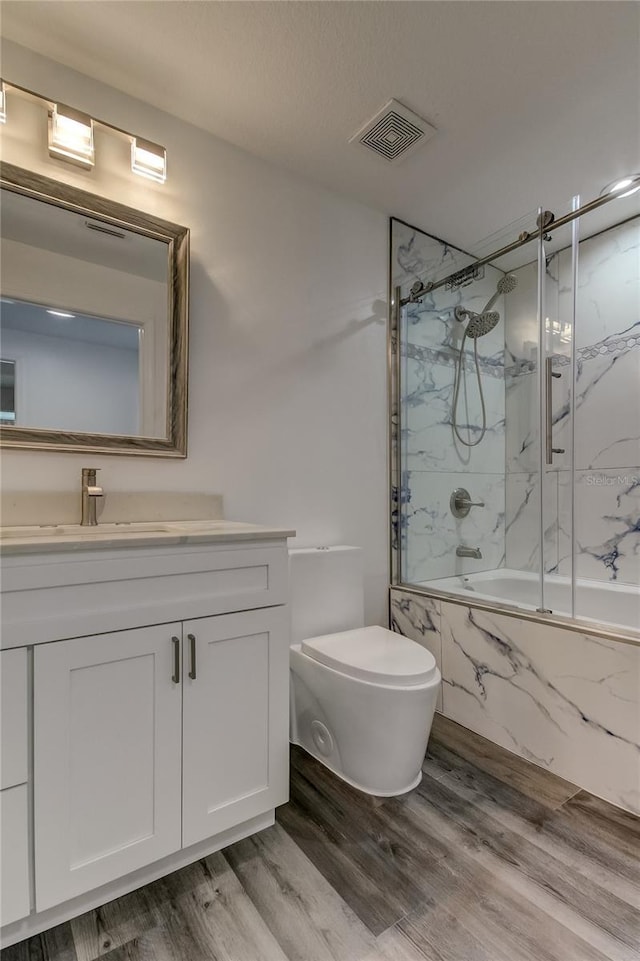 911 8th Ave SW, Largo, FL 33770 - full bathroom featuring wood finished floors, vanity, enclosed tub / shower combo, toilet, and visible vents