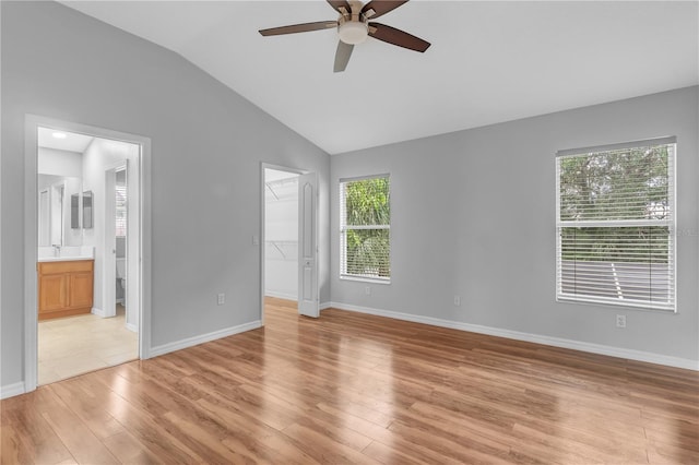 unfurnished bedroom with a walk in closet, light hardwood / wood-style flooring, ensuite bathroom, lofted ceiling, and ceiling fan