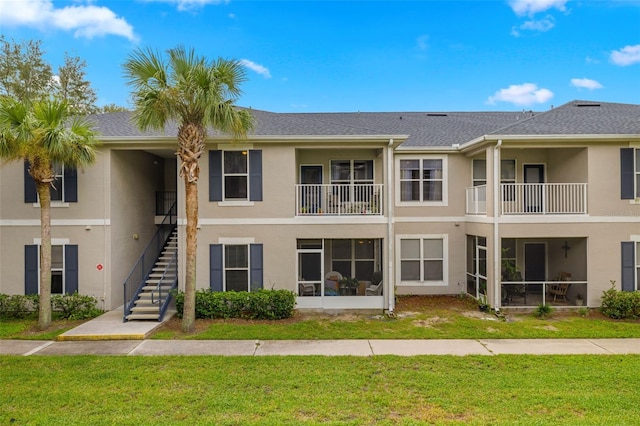 view of front of home featuring a balcony, a front lawn, and a sunroom