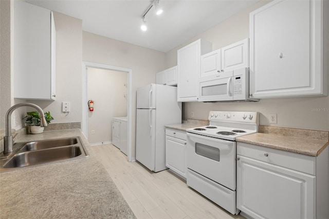 kitchen featuring white cabinets, sink, white appliances, washing machine and clothes dryer, and light hardwood / wood-style floors