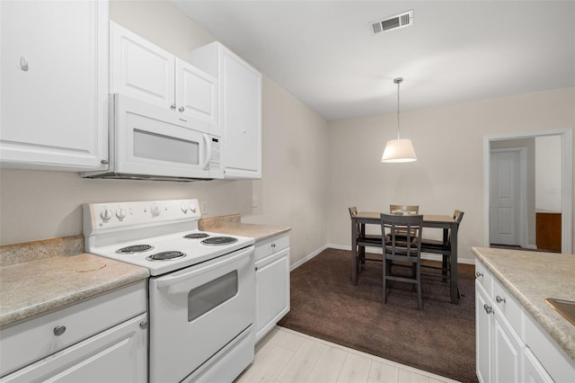 kitchen featuring white appliances, light carpet, pendant lighting, and white cabinets