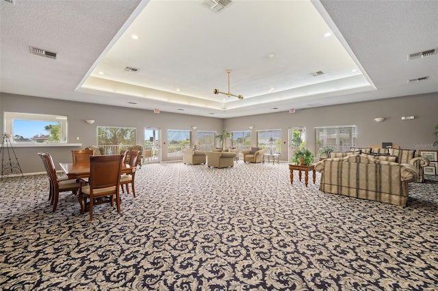 dining area featuring a tray ceiling, a textured ceiling, and carpet flooring