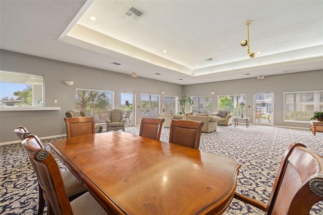 dining area with carpet floors, a tray ceiling, and plenty of natural light