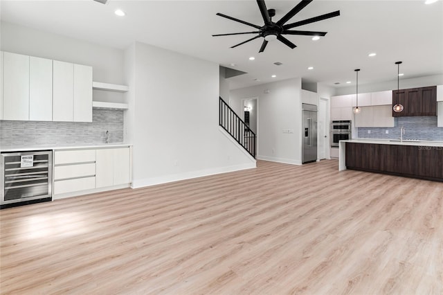 kitchen with hanging light fixtures, beverage cooler, white cabinetry, appliances with stainless steel finishes, and dark brown cabinetry