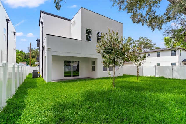 rear view of house with a lawn and central AC