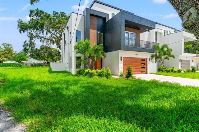 contemporary home featuring a front yard, a balcony, and a garage