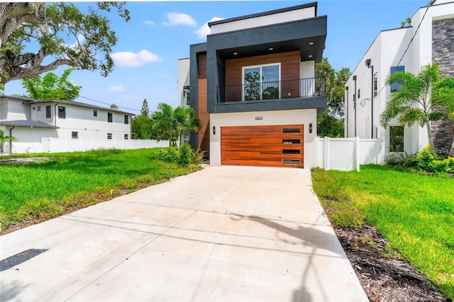 contemporary home featuring a balcony, a front yard, and a garage